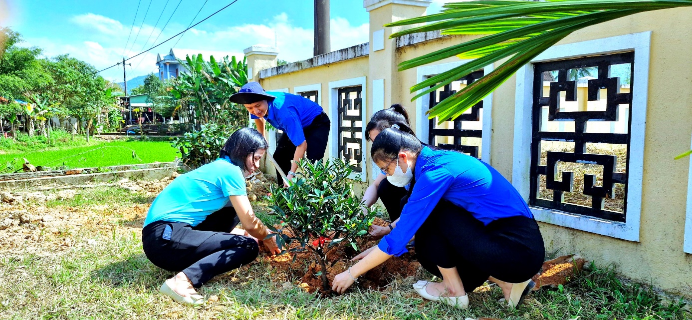 A group of people planting a plant Description automatically generated