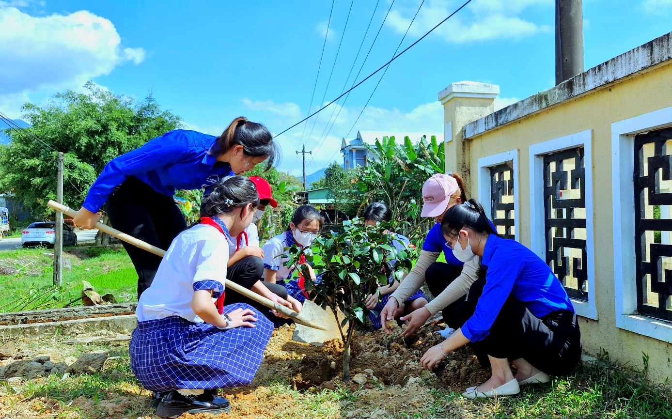 A group of people planting a tree Description automatically generated