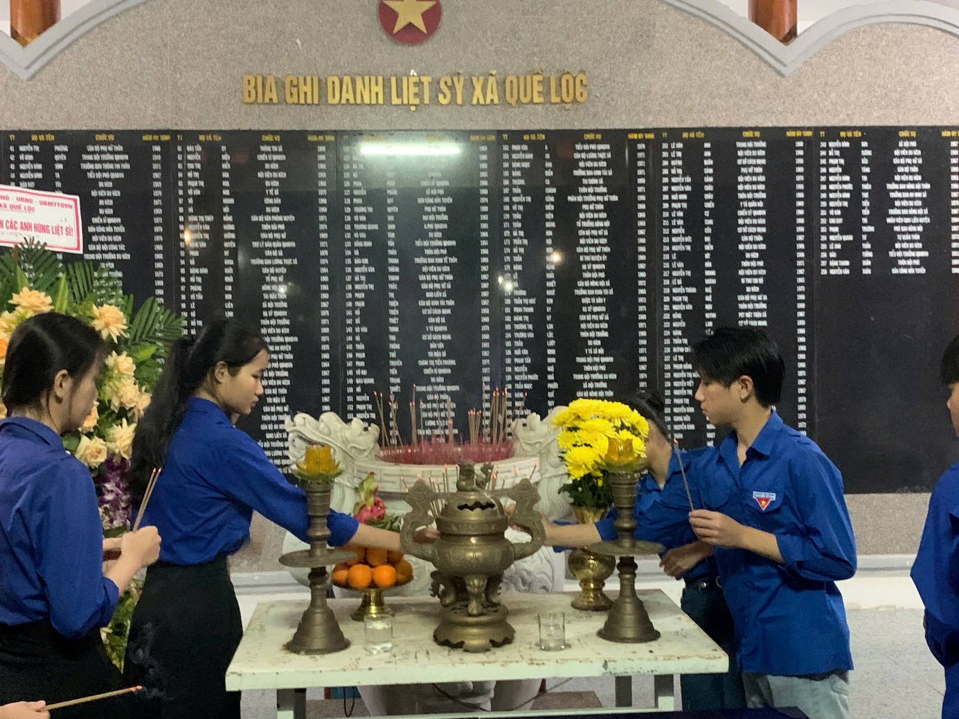 A group of people standing around a table with flowers and candles

Description automatically generated