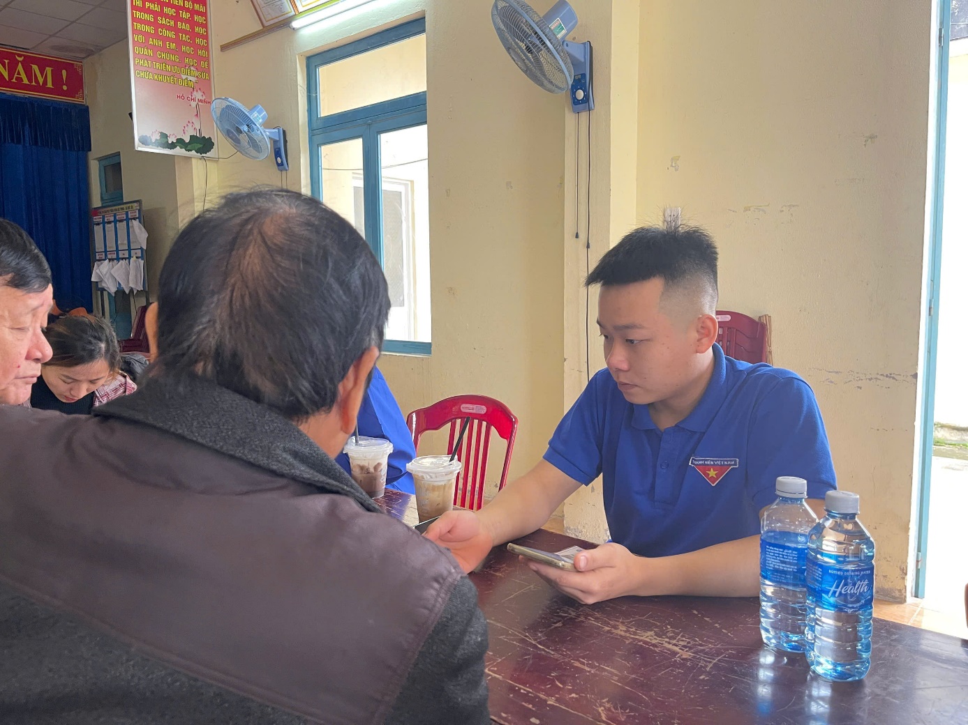 A person sitting at a table with a phone
Description automatically generated