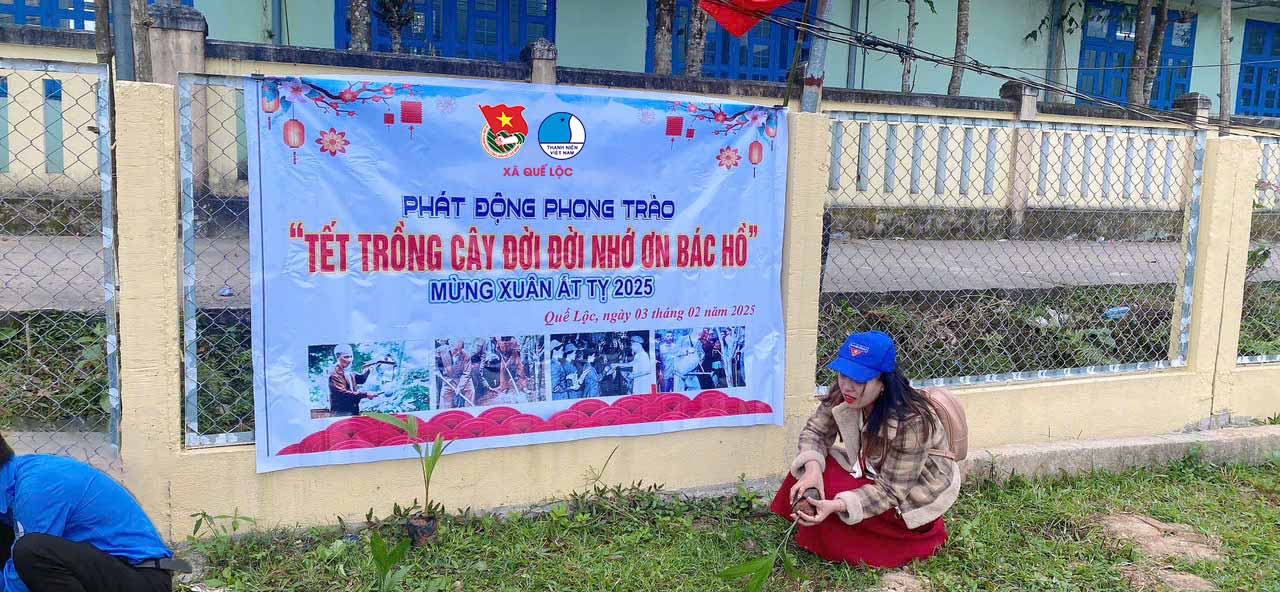 A person sitting on the ground next to a sign
Description automatically generated