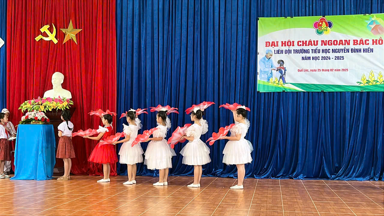 A group of girls in white dresses on a stage Description automatically generated