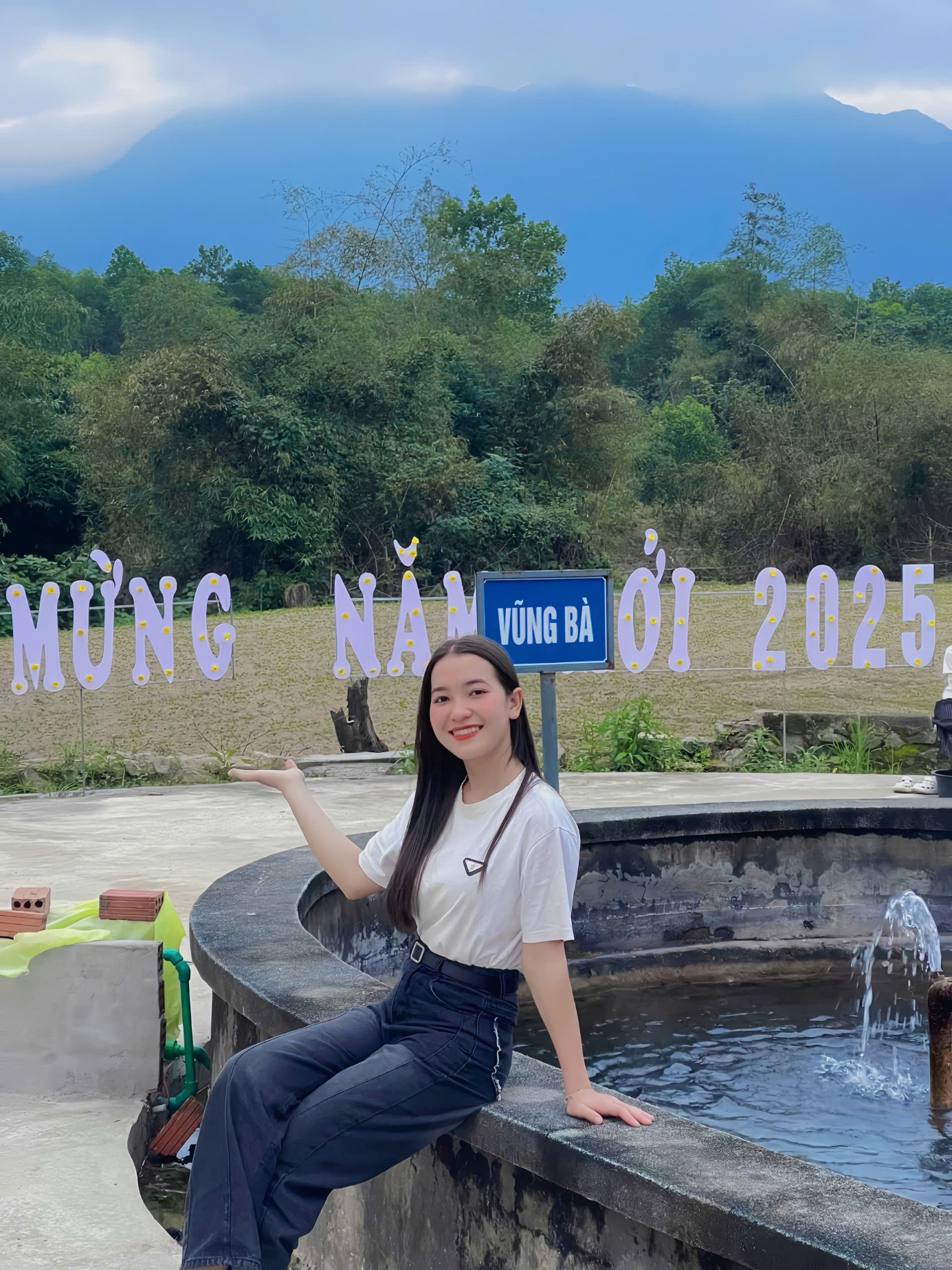 A person sitting on a stone ledge in front of a fountain
Description automatically generated