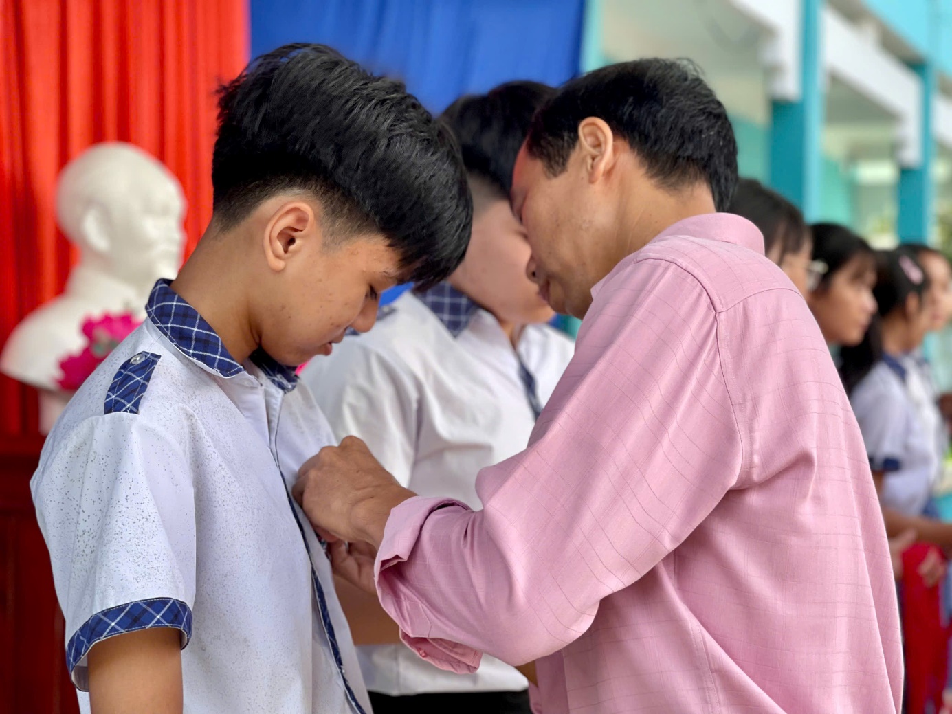 A person helping a child buttoning a shirt Description automatically generated